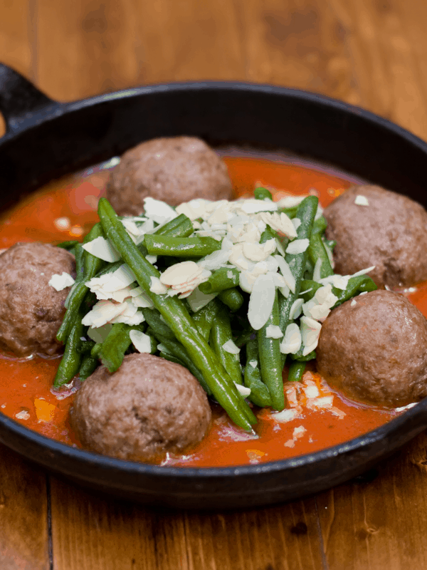 Albóndigas served in tomato sauce with beans and cheese on top. 25 Ideas for the Best Spanish Themed Party 
