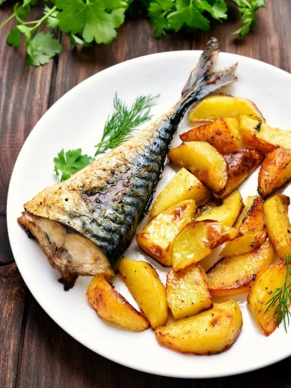 baked Mackerel in foil with potatoes, served on a white plate.