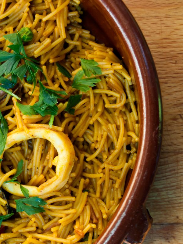 closeup with paella with pasta in a clay bowl