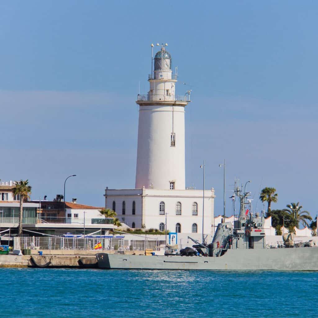 a white lighthouse by a body of water with a ship