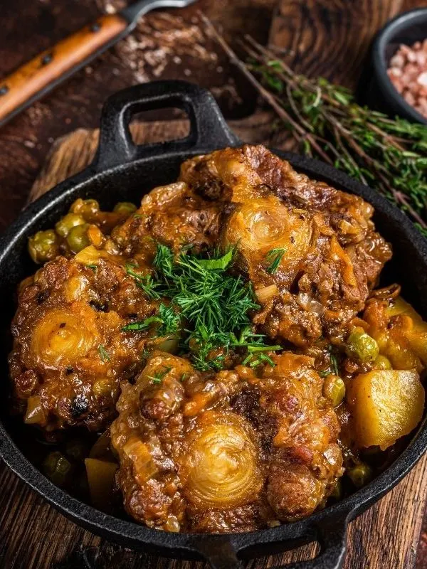 spanish oxtail stew in a pot with herbs next to it on a wooden table. 25 Ideas for the Best Spanish Themed Party 