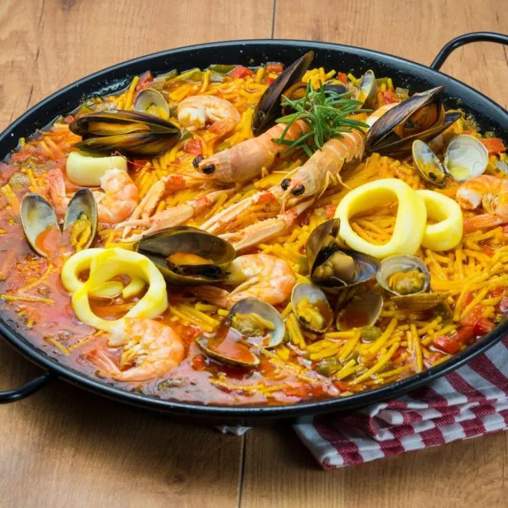 paella with pasta in a pan on a wooden table. - Easy Paella with Pasta [Spanish Recipe]