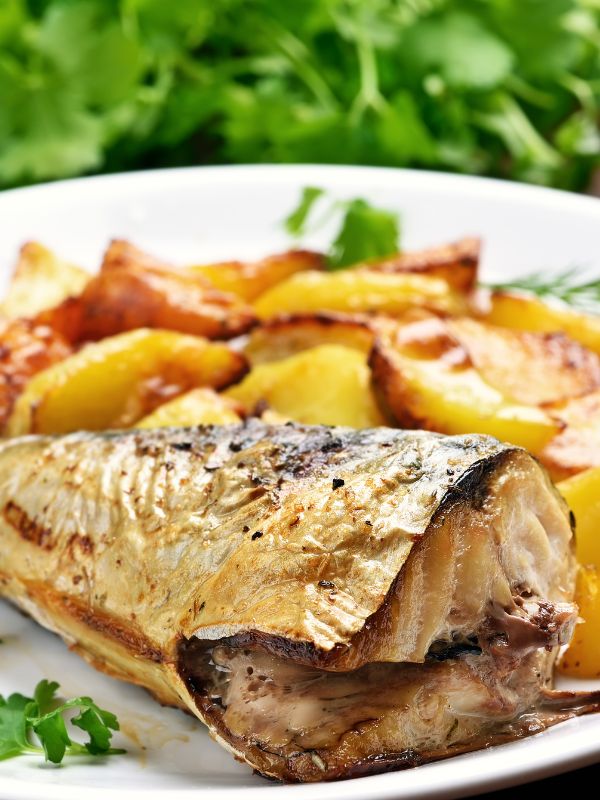 healthy Mackerel recipe on a white plate next to some baked potatoes.
