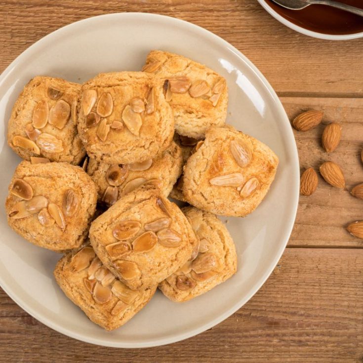spanish almond cookies on a white plate on a wooden table. - Easy Spanish Almond Cookies Recipe