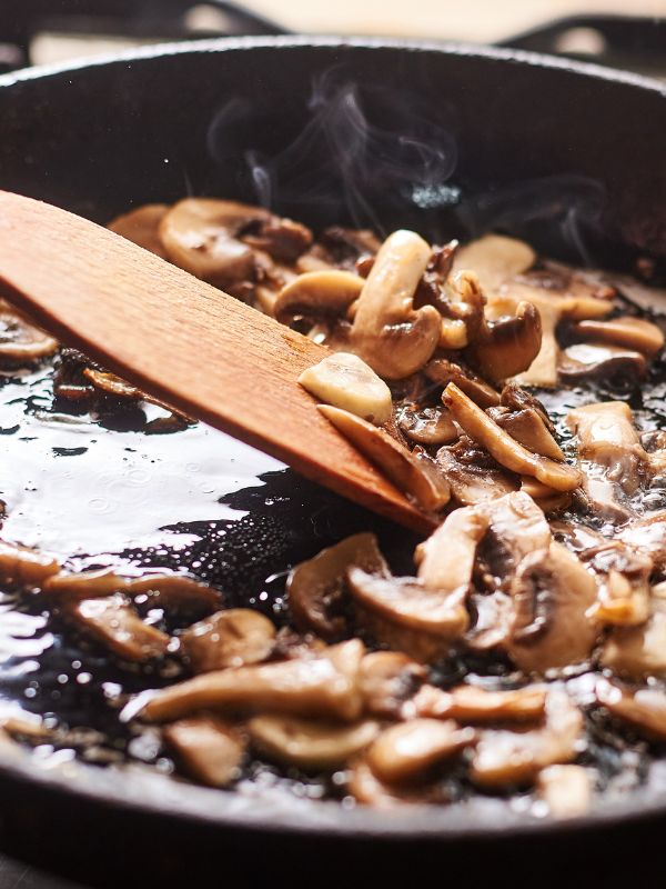 spanish garlic mushrooms being fried in a pan