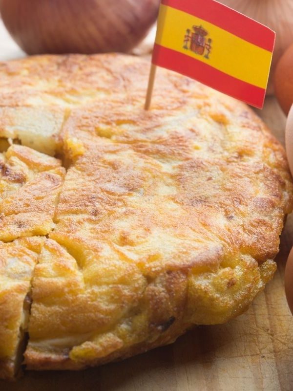 vegan spanish omelette with a spanish flag on top of it on a wooden table.