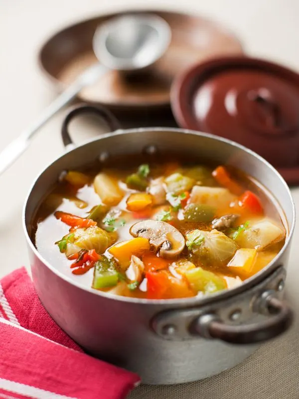 spanish vegetable stew in a pot on a white surface, ready to be served.