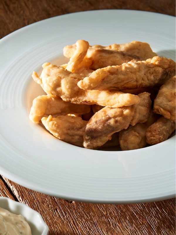 A portion of Spanish fried fish on a white plate.