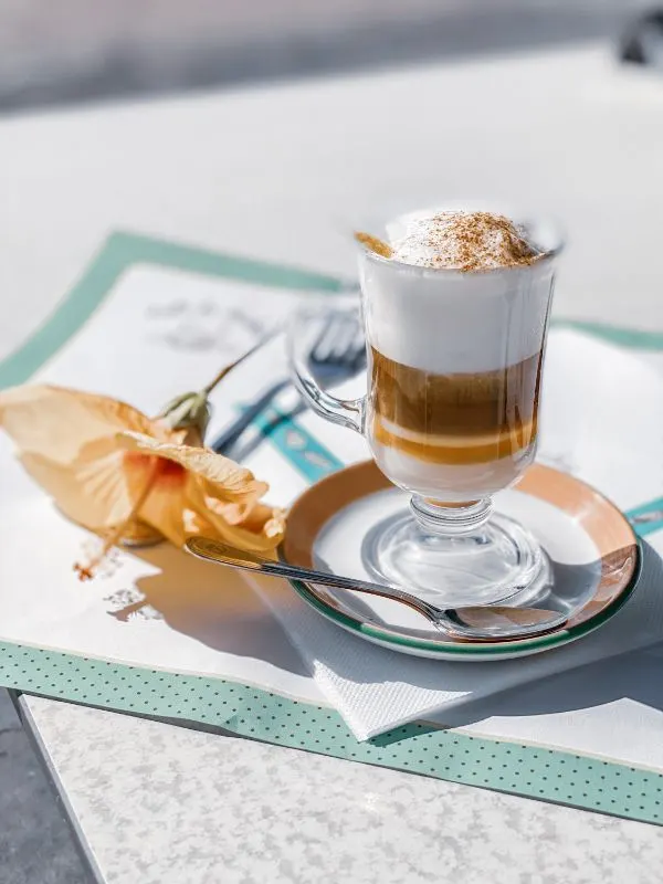 Asiatico cocktail made with condensed milk, coffee, brandy and milk foam and a gumamela flower on a table