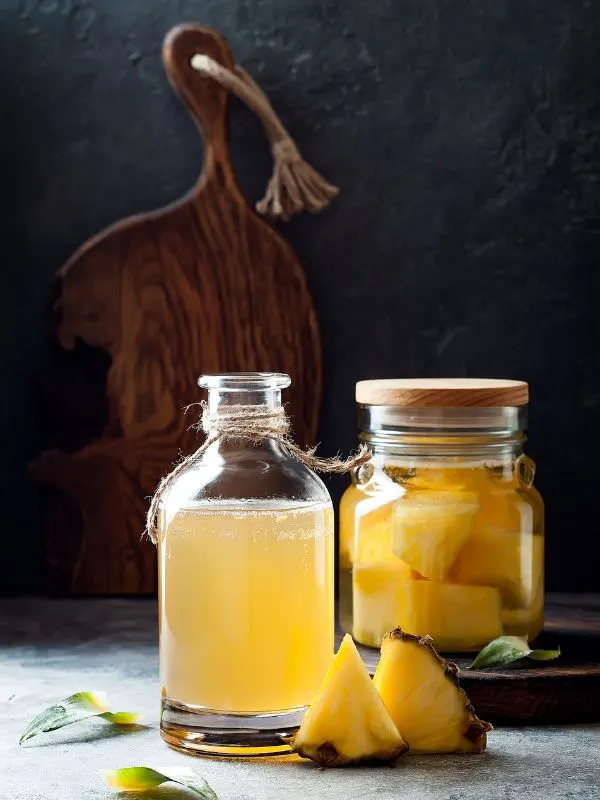 Tepache de pina in 2 jars on a kitchen table. Spanish Fermented Pineapple Juice Recipe