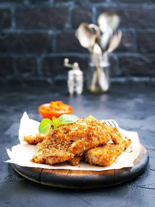 Spanish fried fish on a wooden plate on a kitchen counter.