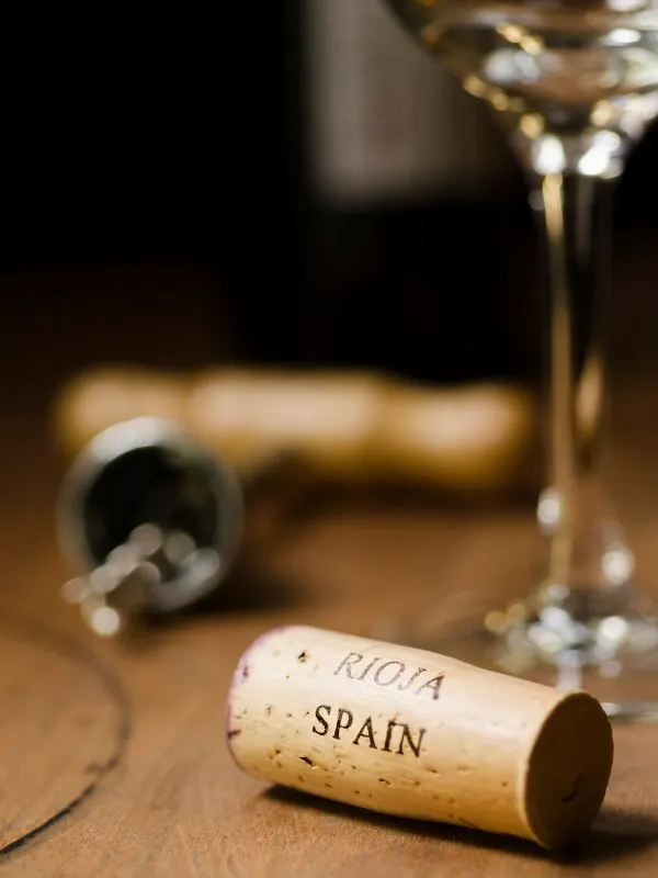 a wine cork with Rioja Spain written on it and a glass of wine in the background.