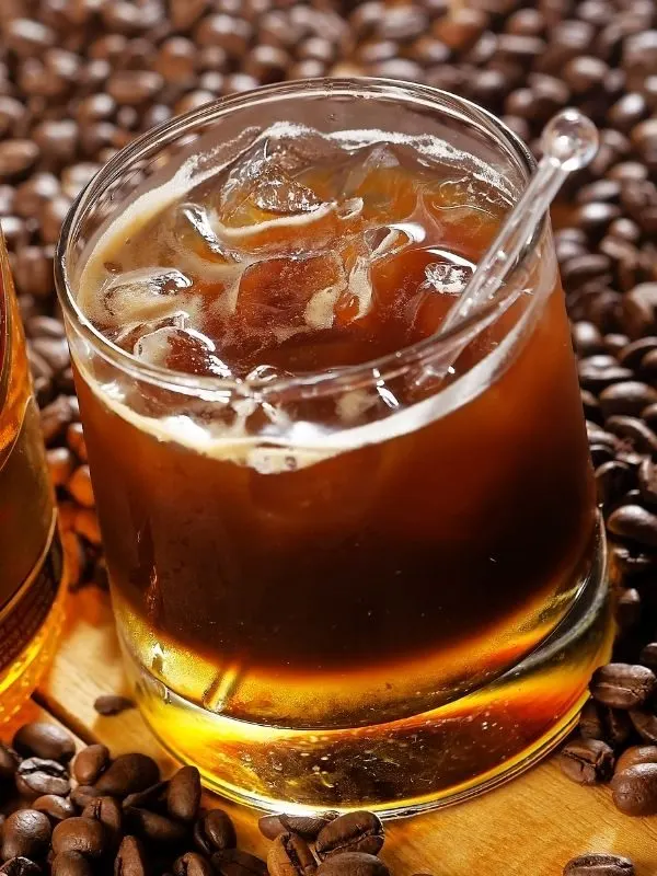 Spanish Coffee Carajillo that is an alcoholic coffee drink on a glass on top of coffee beans