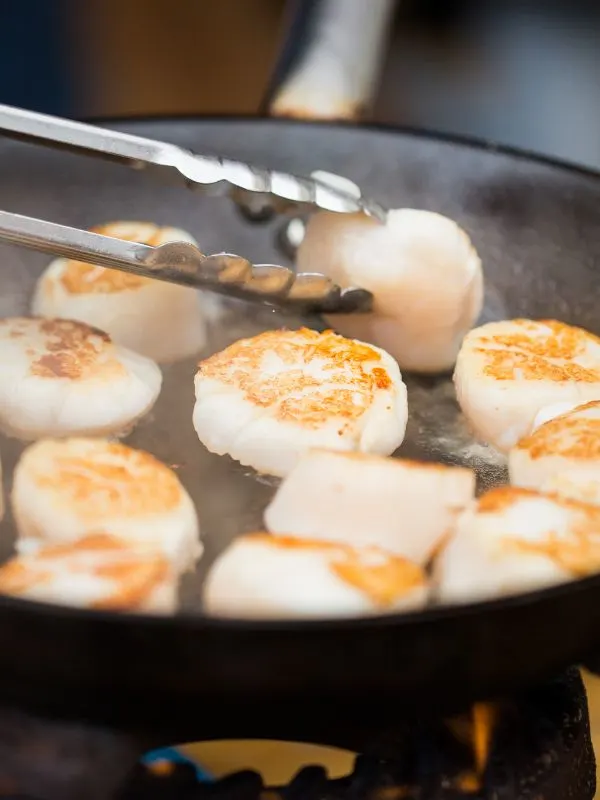 closeup with scallops being fried in a pan