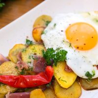closeup with spanish potatoes and eggs on a white plate.