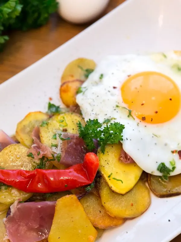 closeup with spanish potatoes and eggs on a white plate. - Best Spanish Potatoes and Eggs Recipe