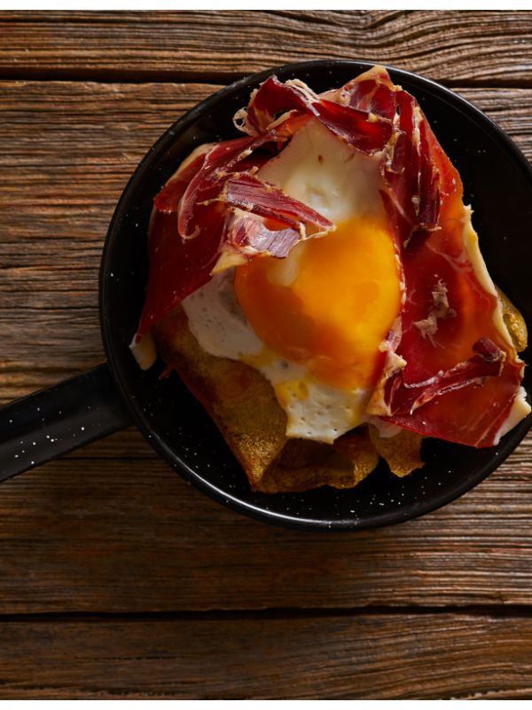 spanish potatoes and eggs in a frying pan on a wooden table.