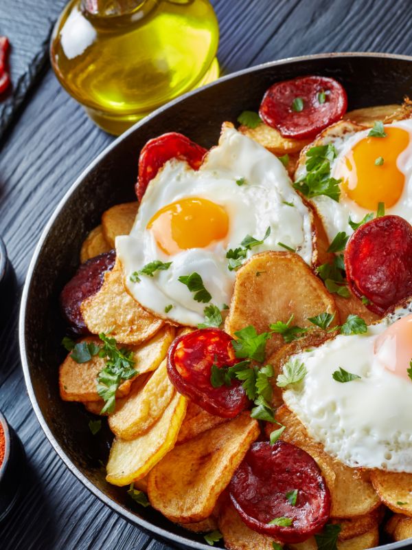 spanish potatoes and eggs in a pan with chorizo slices