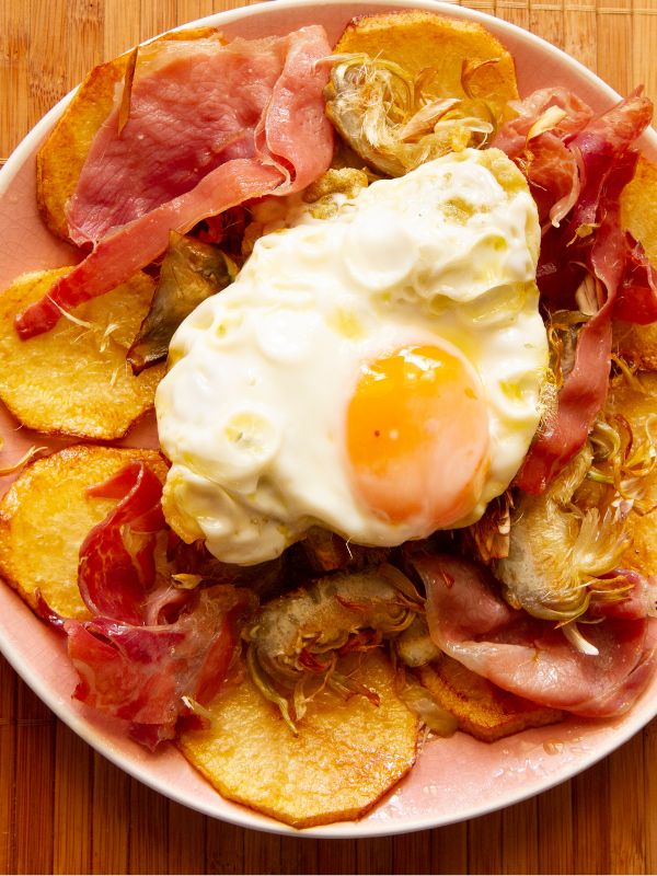 spanish potatoes and eggs on a white plate with wooden background