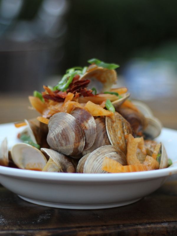 Spanish clams and chorizo in a white bowl.