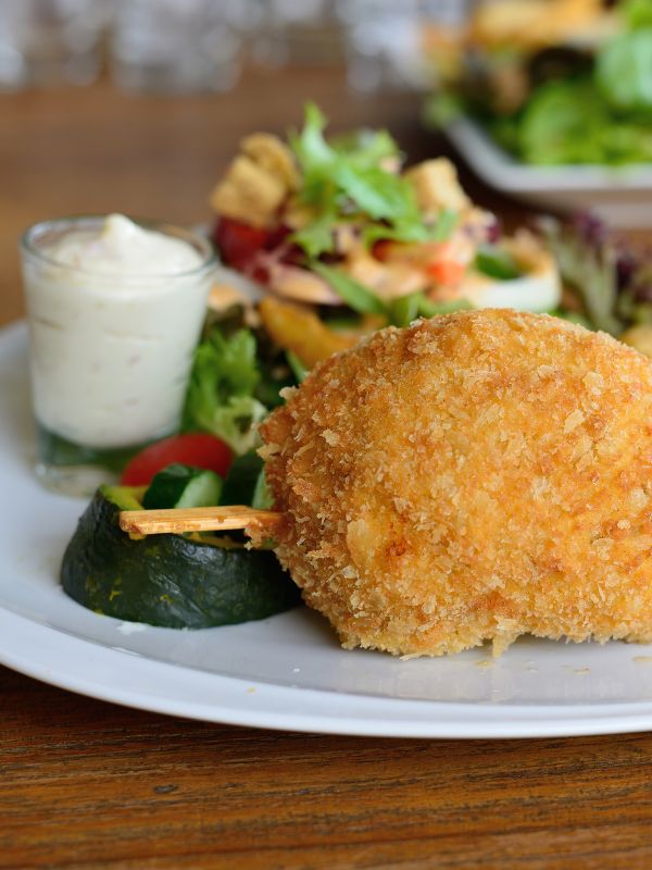 Spanish fried goat cheese on a white plate with sauce and salad