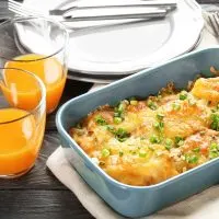 chorizo casserole in a pan next to 2 glasses of orange juice and a plate