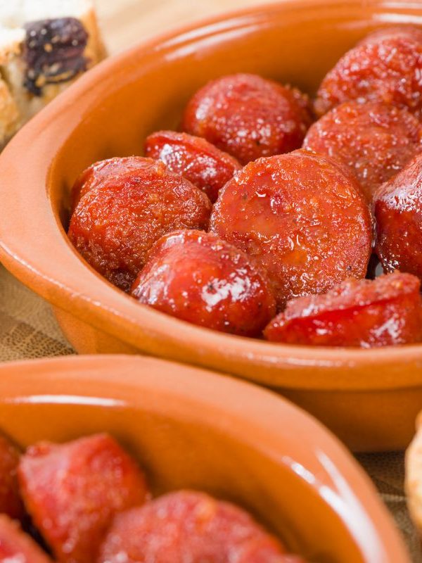 chucks of spansih chorizo recipe with cider served in a clay pot.