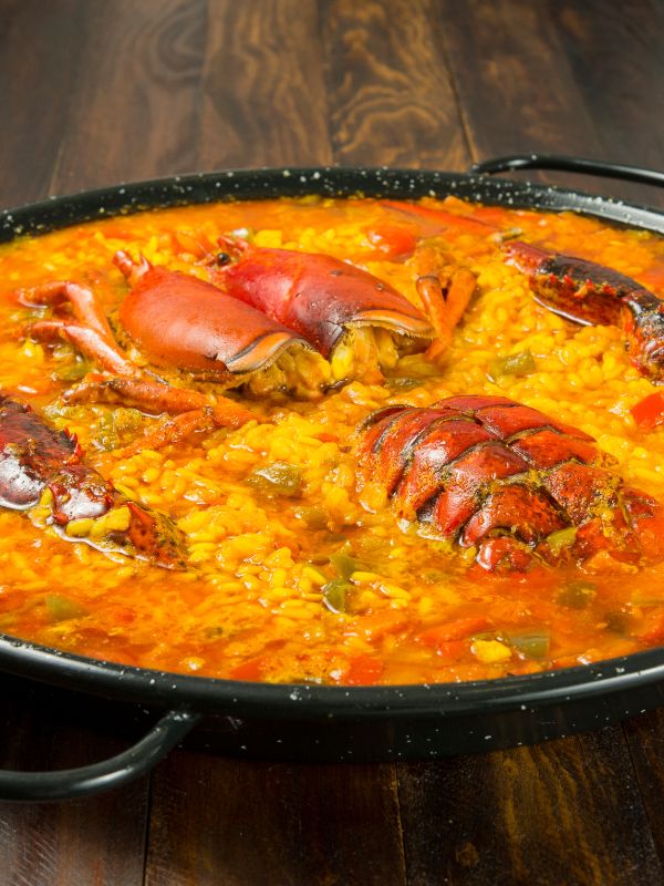 closeup with Spanish Rice with Lobster, Arroz con Bogavante in a pan on a wooden table