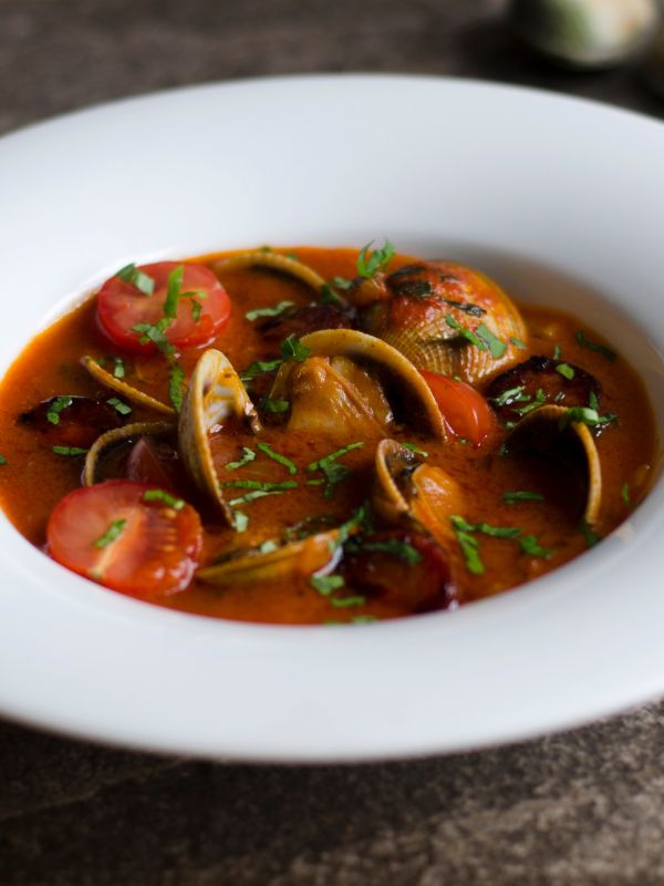 closeup with Spanish clams and chorizo in a serving bowl.