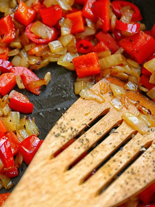 closeup with onion and pepper being fried in a pan for the potaje de vigilia