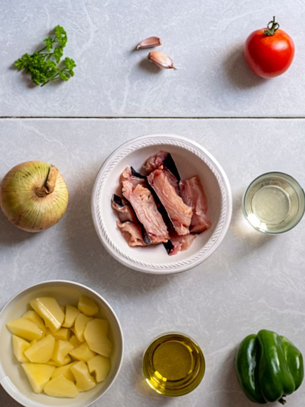 ingredients for marmitako stew, like onion, tuna, potatoes, peppers and tomato.