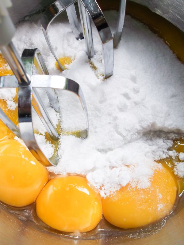 mixing eggs and sugar in a bowl for the spanish orange cake
