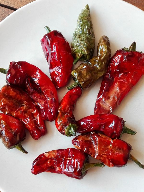 red blistered peppers on a white plate