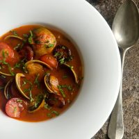 spanish clams with chorizo served in a white bowl