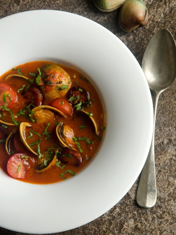 spanish clams with chorizo served in a white bowl. Easy Spanish Clams with Chorizo Recipe