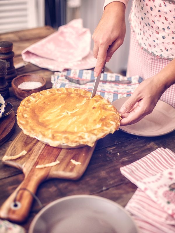 woman cutting a slice of spanish chicken chorizo pie. Spanish Chicken Chorizo Pie Recipe
