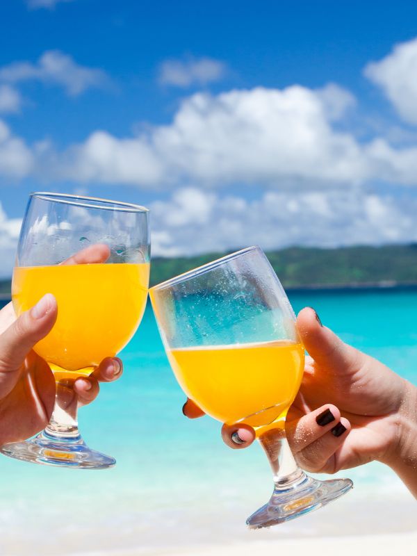 2 people having a toast with agua de valencia on a beach