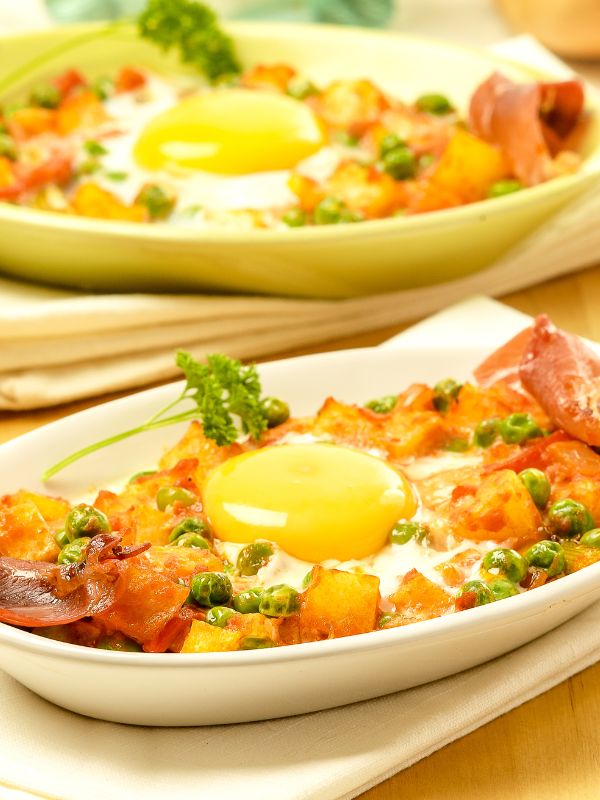 2 plates with Huevos a la flamenca, potato on a plate topped with eggs