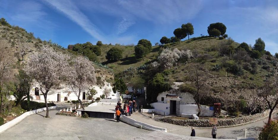 a view of the Cave Museum with a mountain covered in green and trees