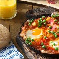 Huevos a la flamenca in a pan next to a glass of orange juice