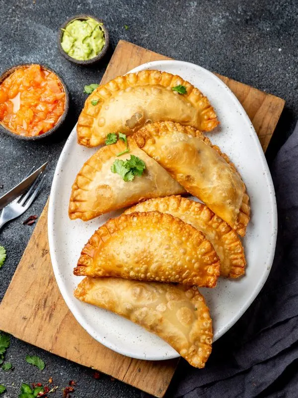 cheese empanada recipe on a white plate served with sauces.