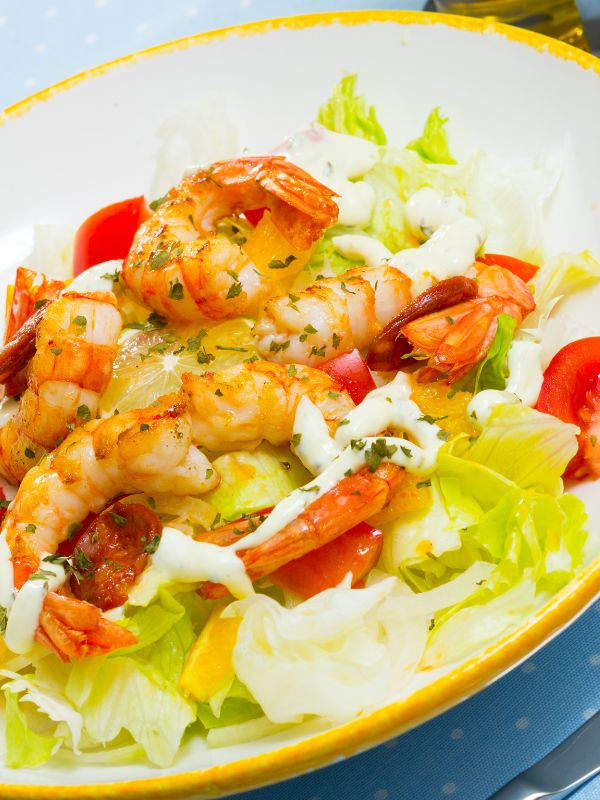 closeup with chorizo and shrimp recipe served on a bed of salad.
