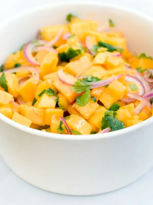 closeup with ensalada de mango in a white bowl.