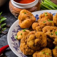 fried cauliflower recipe in a bowl next to some red sauce