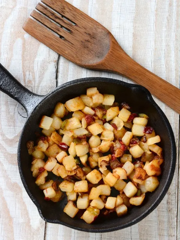 fried potatoes in a pan for potatoes and eggs on a wooden table for Huevos a la flamenca