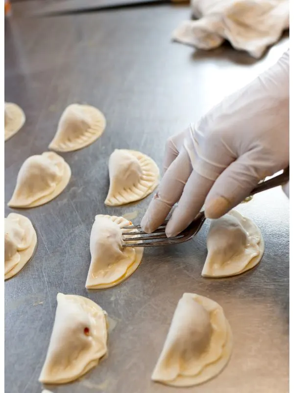 fruit empanada recipe being pinched with a fork