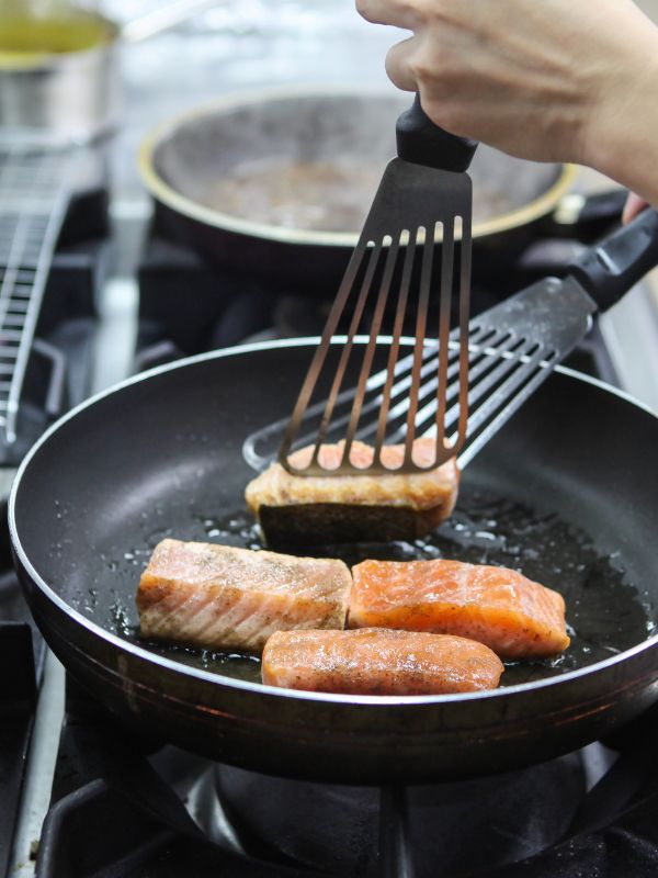 frying salmon in a pan for the ensalada de salmon