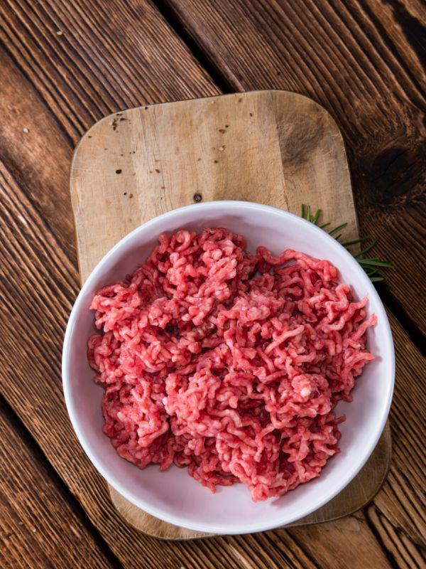 minced beef meat in a bowl on a wooden table.