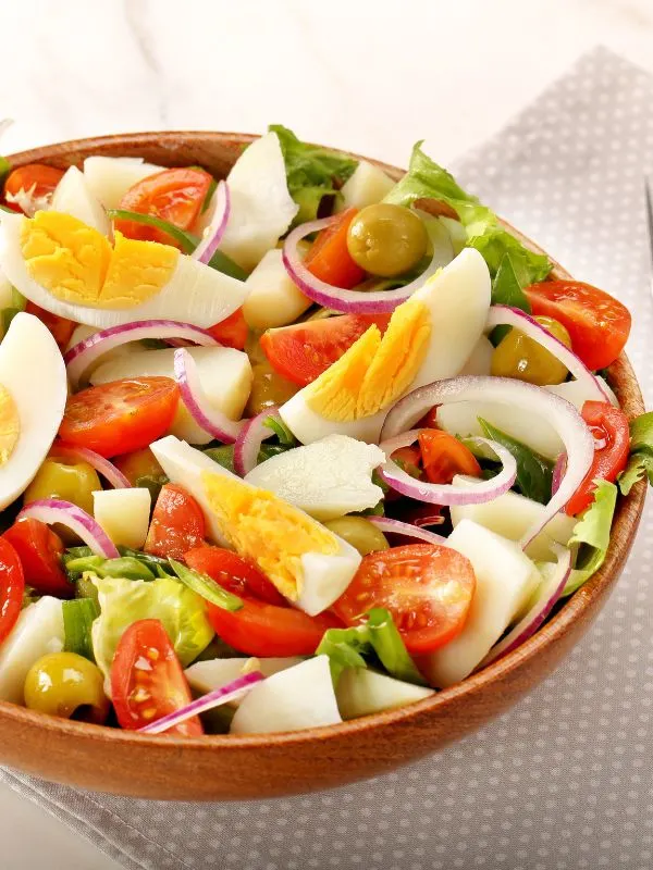 spanish mixed green salad in a wooden bowl
