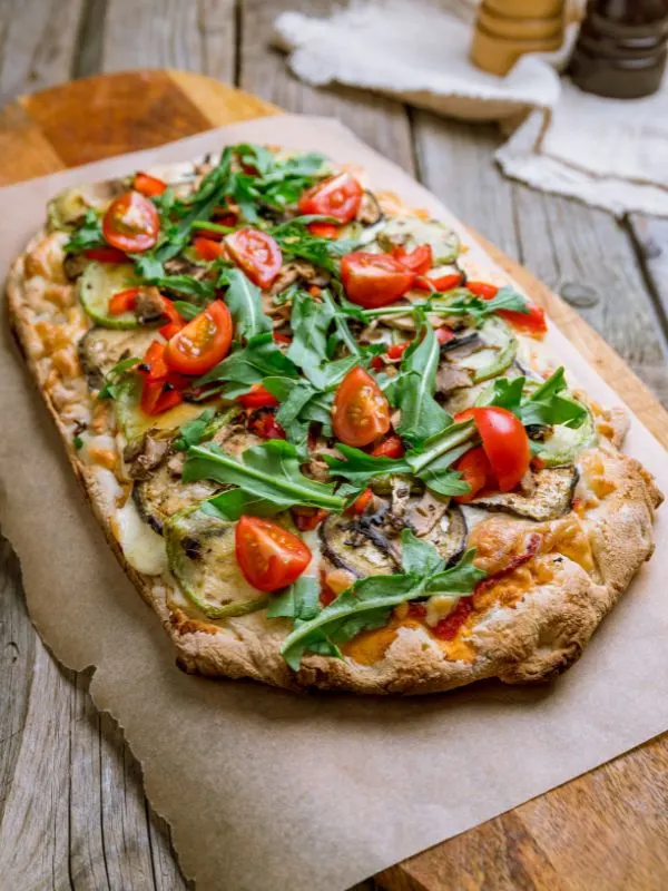 spanish pizza recipe with various vegetables on a wooden board.